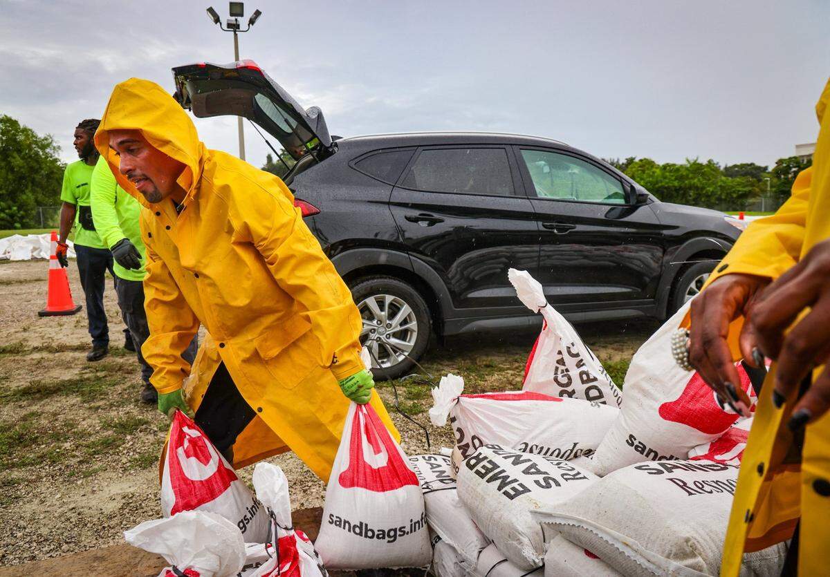 El empleado de Obras Públicas Michael Pérez (izq), ayuda en la entrega de bolsas de arena en la Ciudad de Miami Garden el domingo 6 de octubre de 2024, por el huracán Milton.