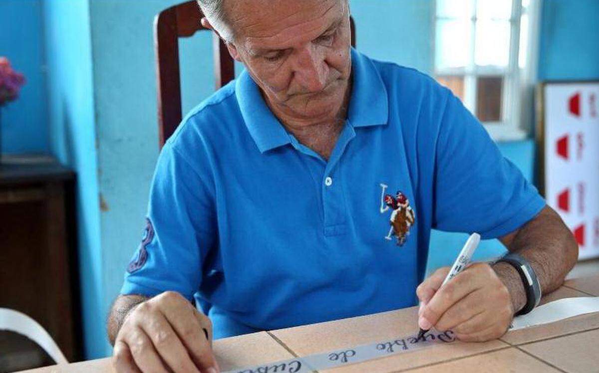 Fotografía fechada el 23 de mayo de 2018 que muestra al informático Carlos Parra mientras escribe en la cinta de una corona de flores durante una entrevista con Efe en la provincia de Holguín (Cuba).