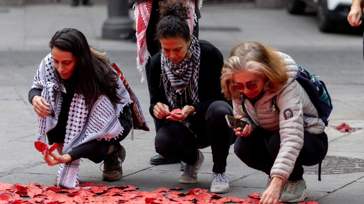 Tres mujeres depositan flores de papel para conmemorar el segundo aniversario de la guerra en Gaza y oponerse a lo que activistas describen como el genocidio de palestinos, el lunes 6 de octubre de 2025, en Madrid, España.