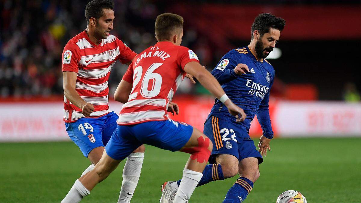El mediocampista del Real Madrid Isco (der.) conduce el balón ante Isma Ruiz (centro) y Angel Montoro, del Granada, en el partido de la liga española celebrado el 21 de noviembre de 2021 en Granada.