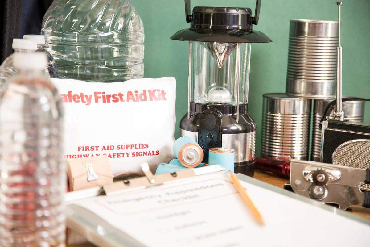 Una pila de suministros para emergencias y desastres naturales, incluyendo: lista de verificación, linterna, botiquín de primeros auxilios, linterna, botellas de agua, alimentos enlatados, abrelatas, radio, mochila, baterías. En temporada de huracanes, es mejor estar preparado. 