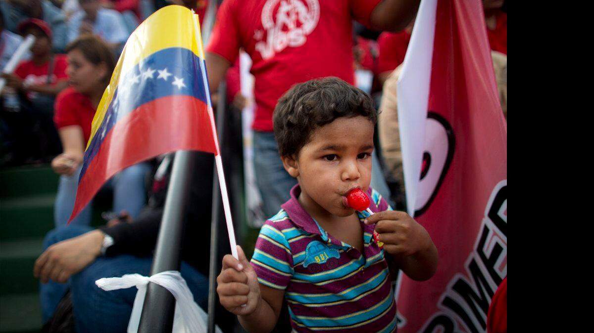 Un niño disfruta un lollipop y sostiene una bandera venezolana en una manifestación en el palacio presidencial de Miraflores en Caracas, Venezuela, miércoles, 18 de marzo 2015.
