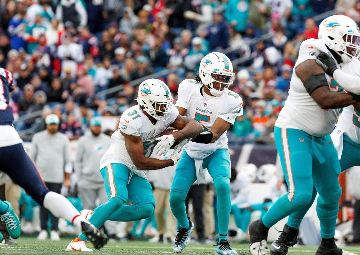 El quarterback de los Dolphins Teddy Bridgewater (5) le da el ovoide al running back Raheem Mostert en una jugada en el tercer cuarto del partido ante los Patriots, celebrado el 1ro de enero de 2023 en Foxborough, Massachusetts.