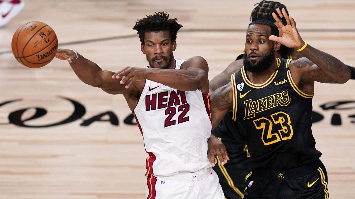 El delantero del Heat, Jimmy Butler (izq.), pasa el balón ante el jugador de los Lakers LeBron James, durante las Finales de la NBA. el 9 de octubre de 2020 en Lake Buena Vista, Florida.