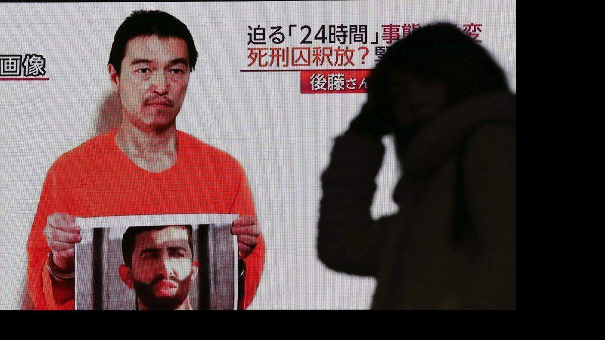 En esta foto de archivo del miércoles, 28 de enero 2015, una persona se ve en frente de una gran pantalla de televisión que emite un programa de noticias en Tokio informando sobre un video publicado en YouTube por yihadistas el martes 27 de enero, que pretende mostrar una foto fija de rehén japonés Kenji Goto sosteniendo lo que parece ser una foto del piloto de Jordania, el teniente Muath al-Kaseasbeh.