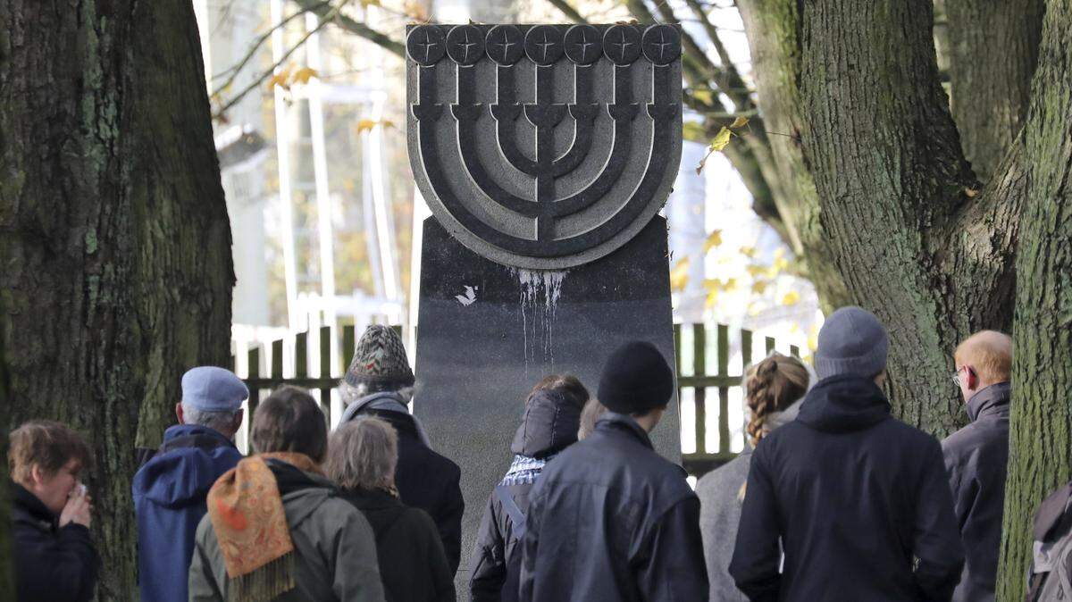 Un grupo de personas participa en el evento de recordación de la Noche de los Cristales Rotos, en el cementerio judío de Rostock, Alemania, el domingo 10 de noviembre de 2019. Kristallnacht, como es conocido en alemán, fue una serie de linchamientos y ataques contra la comunidad judía en la Alemani nazi el 9 y 10 de noviembre de 1938.