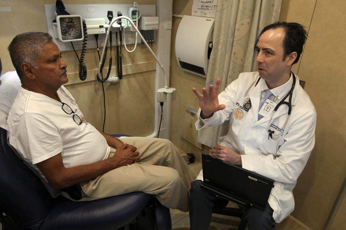 El Dr. Fred Anderson atiende a Sharma Boboolal en una clínica móvil en Miami Gardens. Anderson es un médico de familia quien dijo que su trabajo de cuidar a pacientes sin seguro y de bajos ingresos, entre ellos muchos inmigrantes, se ha dificultado debido a los cambios propuestos a una regla federal sobre la carga pública y el aumento de la retórica contra los inmigrantes.