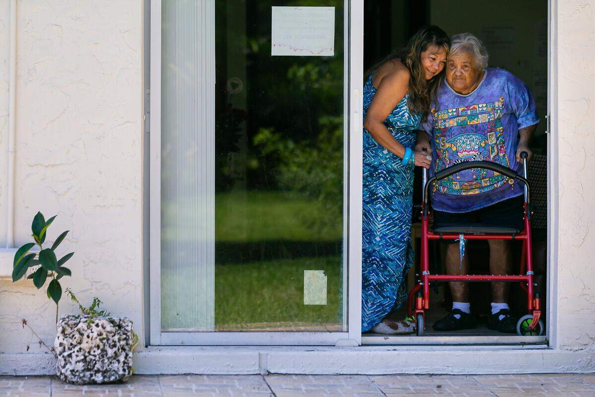 Mily López, de 57 años, a la izquierda, le da un abrazo a su madre, Milagro Morales, en su casa en el barrio Fontainebleau de Miami el sábado 9 de mayo de 2020. López cuida a su madre de 81 años, que tiene demencia, y a su suegro de 95 años.