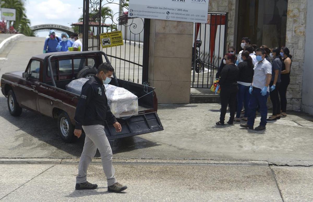 Familiares y personal de un cementerio aguardan a enterrar a posibles víctimas del coronavirus en Guayaquil, Ecuador, el 1 de abril de 2020. Los ataúdes están envueltos en plástico como precaución adicional contra el contagio del coronavirus..