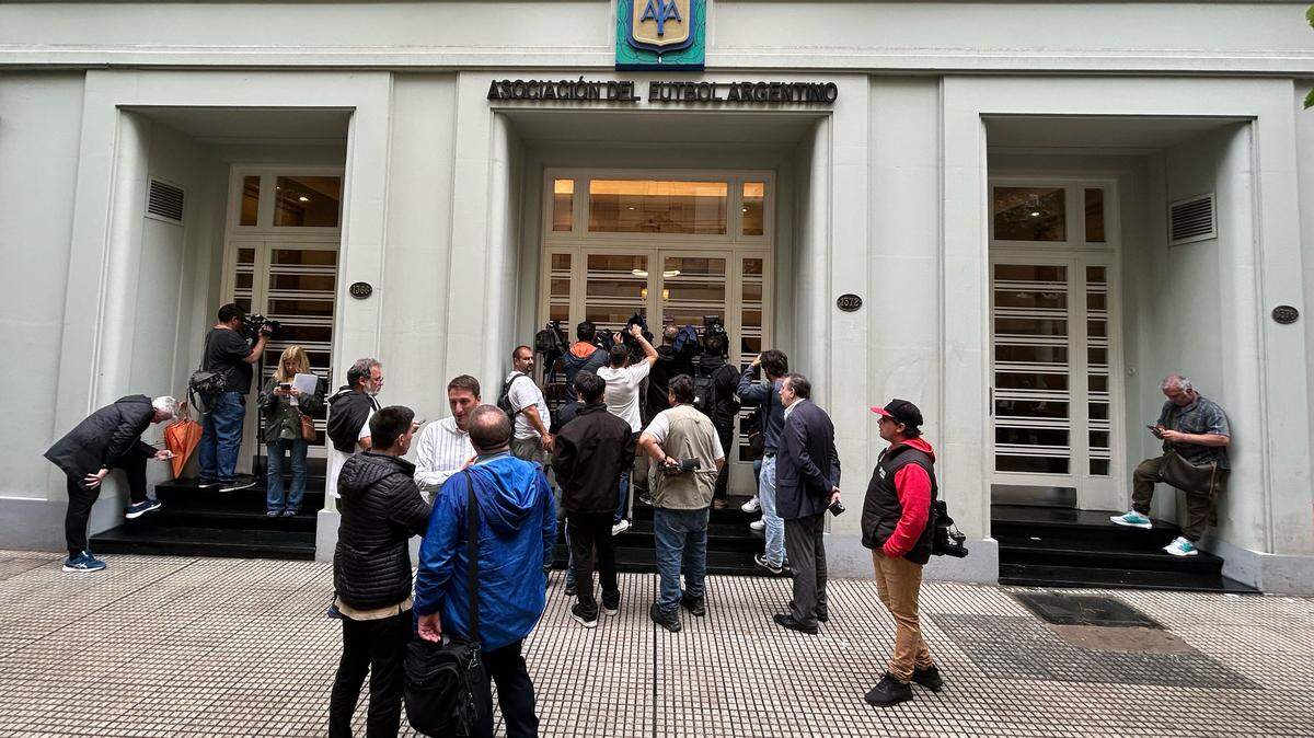 Journalists peek from outside the entrace of the Argentine Football Association (AFA) headquarters, where Federal Police are raiding in Buenos Aires on December 9, 2025. (Photo by JUAN MABROMATA / AFP via Getty Images)