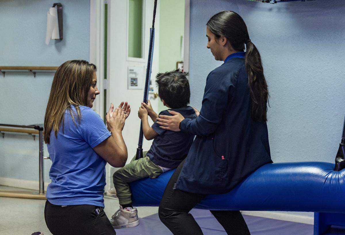Charrie Sanchez (izq), Directora de Terapia en Patches, comparte con Savannah Sánchez, estudiante de Terapia Ocupacional de FIU, mientras capacita a uno de los pacientes que asisten a la organización sin fines de lucro que ofrece a las familias de niños gravemente enfermos atención diaria 12 horas al día, 5 días a la semana, desde el nacimiento hasta los 21 años, independientemente de la capacidad de pago o cobertura de seguro, en Florida City.