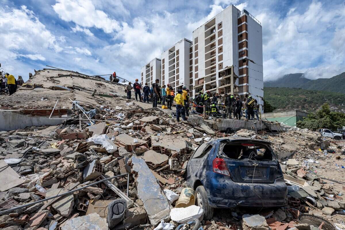 Rescuers work on the rubble of a collapsed building near a damaged vehicle in Caraballeda, La Guaira state, Venezuela, on June 28, 2026, following earthquakes. Thousands of rescuers, relatives and volunteers dig day and night through mounds of concrete to find survivors of the earthquakes that struck Venezuela more than three days ago, leaving nearly 1,500 dead and tens of thousands missing. (Photo by Miguel MEDINA / POOL / AFP via Getty Images)