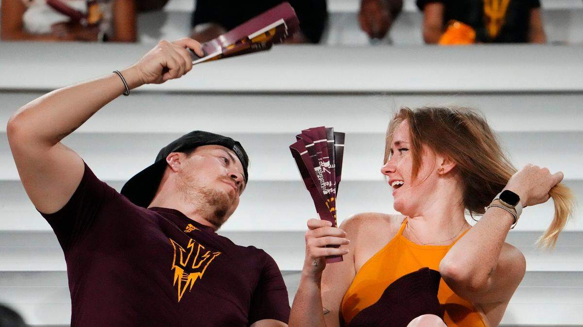 Dos fanáticos usan abanicos para tratar de refrescarse durante un partido de fútbol americano entre Oklahoma State Cowboys y Arizona State Sun Devils, en el Estadio Mountain America in Tempe, Arizona, el 9 de septiembre de 2023.