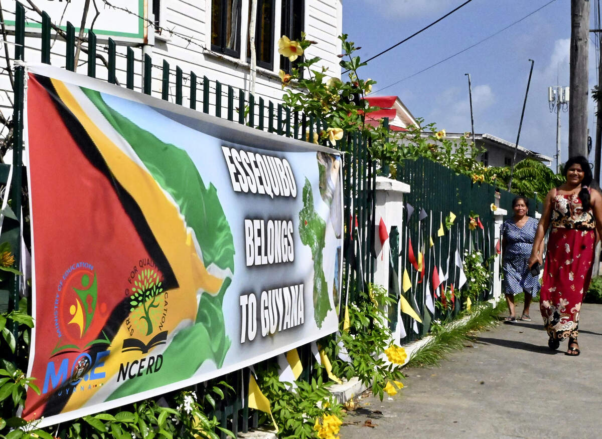 Dos mujeres caminan cerca de una pancarta que dice “El Esequibo es nuestro”, en Georgetown, Guyana, el 6 de enero de 2024.