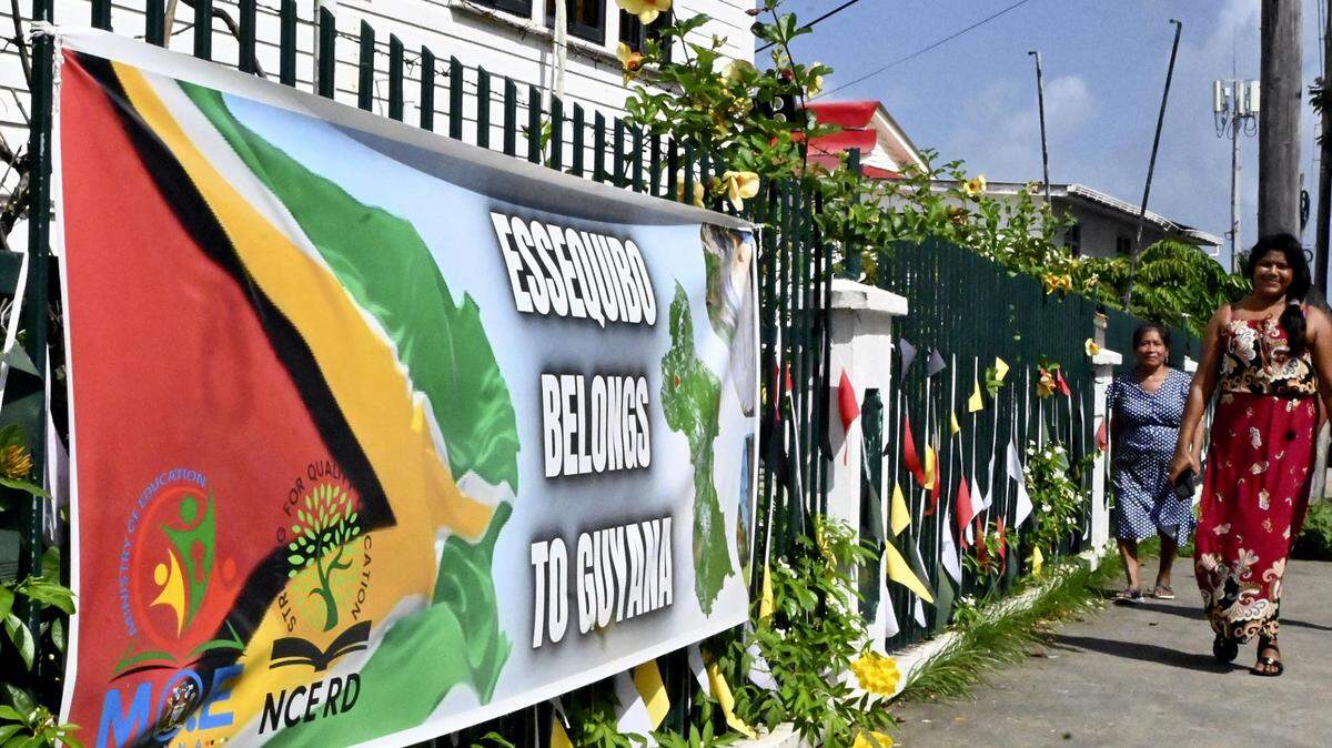 Dos mujeres caminan cerca de una pancarta que dice “El Esequibo es nuestro”, en Georgetown, Guyana, el 6 de enero de 2024.