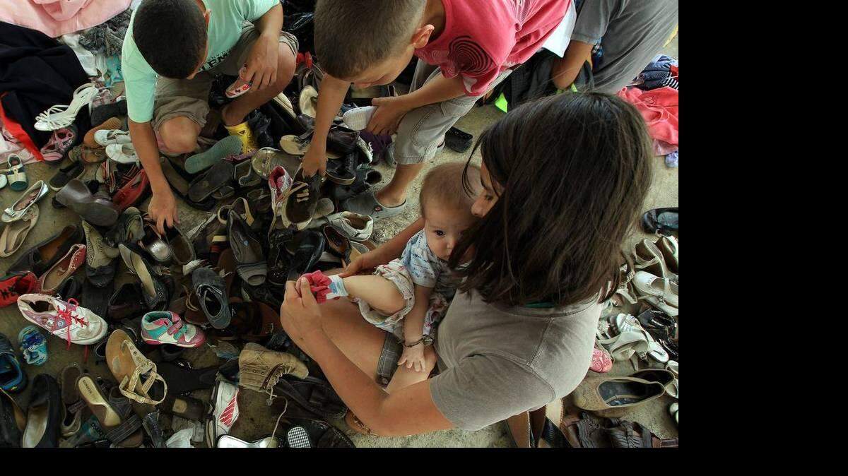 ARCHIVO - Una niña colombiana busca zapatos para una bebé de nueve meses en el albergue El Morichal, en Cucutá, Colombia, el jueves 27 de agosto de 2015.