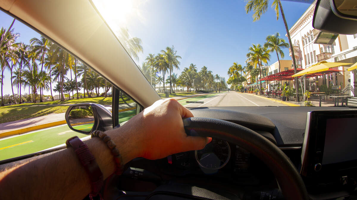 Hombre conduciendo un auto por Ocean Drive en el distrito Art Deco de Miami Beach, Miami.