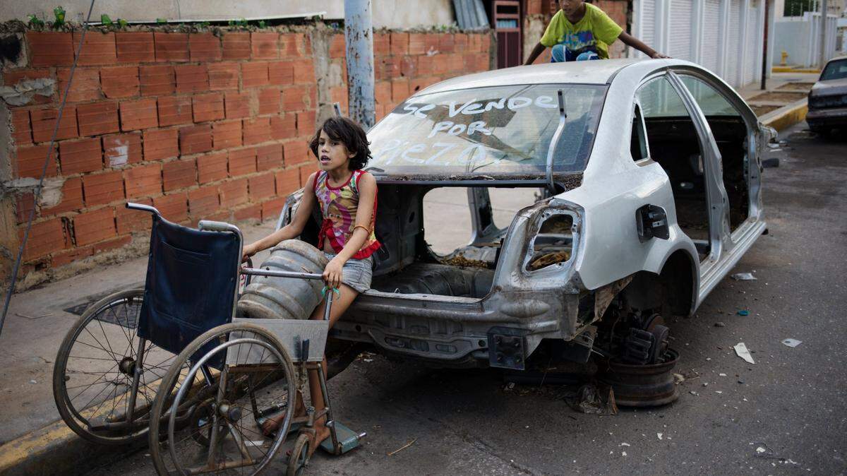 La pobreza en Venezuela ha crecido durante los 20 años del régimen chavista. En la foto, una niña usa la silla de ruedas de su abuela para transportar un botellón de agua, distribuida debido a la grave escasez del vital líquido, el 14 de noviembre de 2019, en Maracaibo, Venezuela.