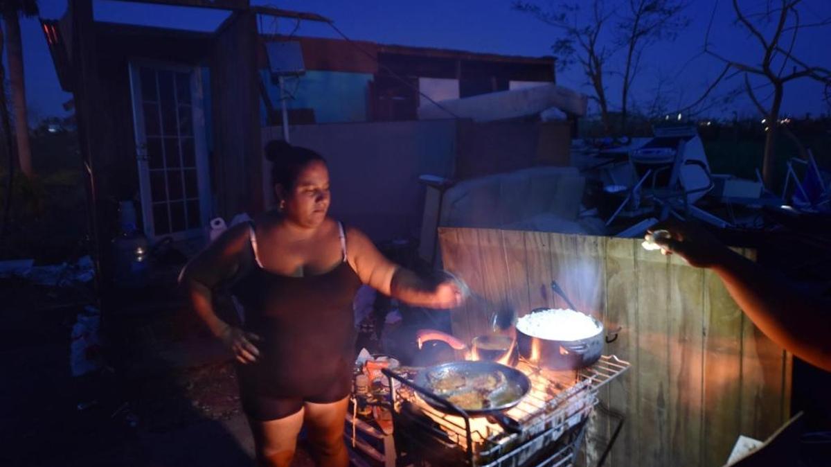 María prepara comida cerca de su casa que fue destruida por el huracán María en Puerto Rico.