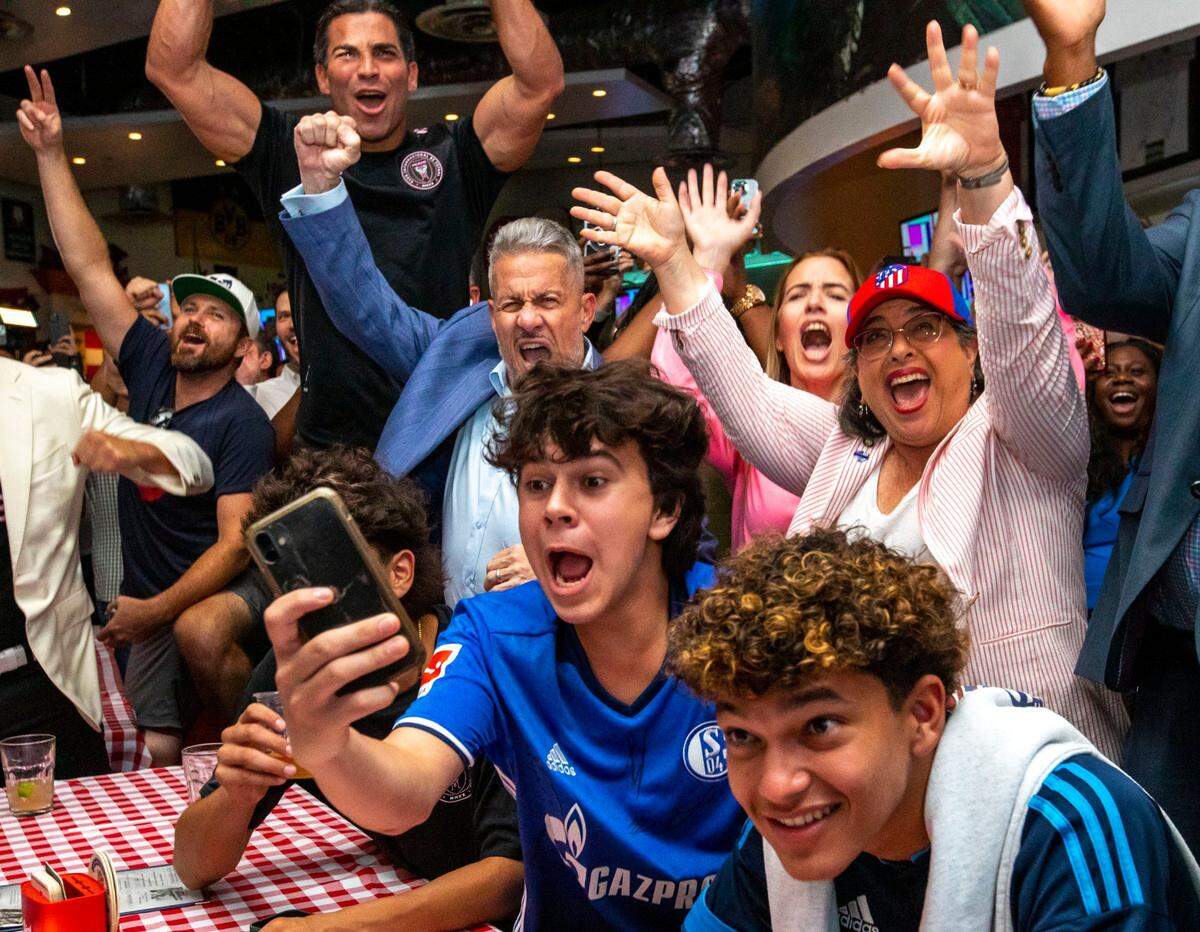 La alcaldesa de Miami Dade Daniella Levine Cava (der.), el alcalde de Miami Francis Suárez (izq.) y el presidente de la Junta de Comisionados del condado José Díaz (centro) celebran con un grupo de fanáticos la elección de Miami como sede de la Copa Mundial de fútbol 2026, en el restaurante Fritz & Franz Bierhaus en Coral Gables, Florida, el 16 de junio de 2022.