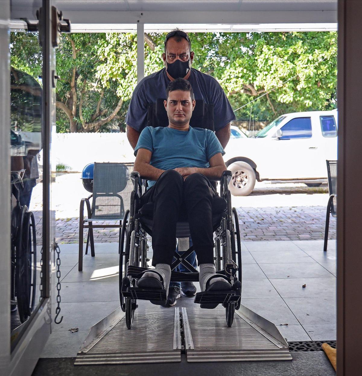 Carlos Corpas Jr., 27, is pushed by his father up a ramp to his new large bathroom on the perimeter of his father’s home. A car accident left him a quadriplegic.