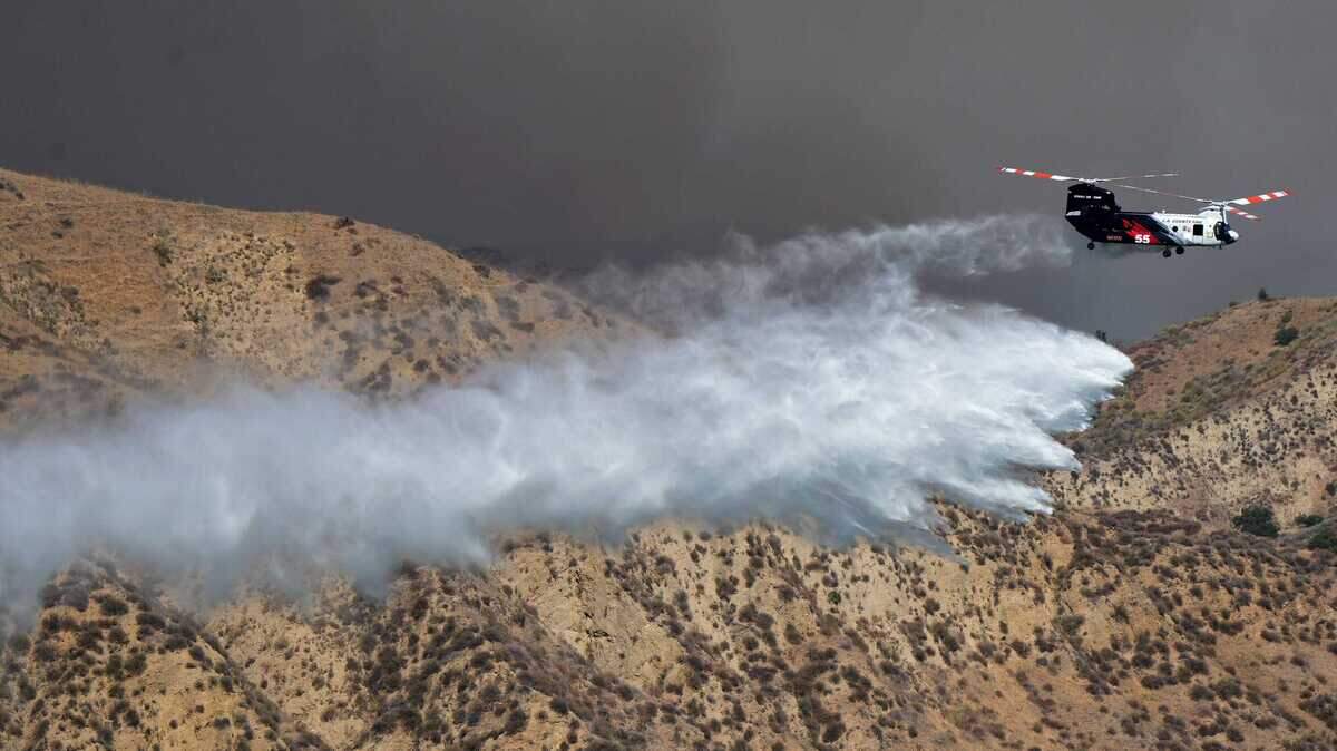 Un helicóptero arroja agua sobre el incendio Canyon, que comenzó al sureste del lago Piru alrededor de la 1:30 p. m. del 7 de agosto de 2025, en una zona remota de las montañas entre Piru y la Interestatal 5.
