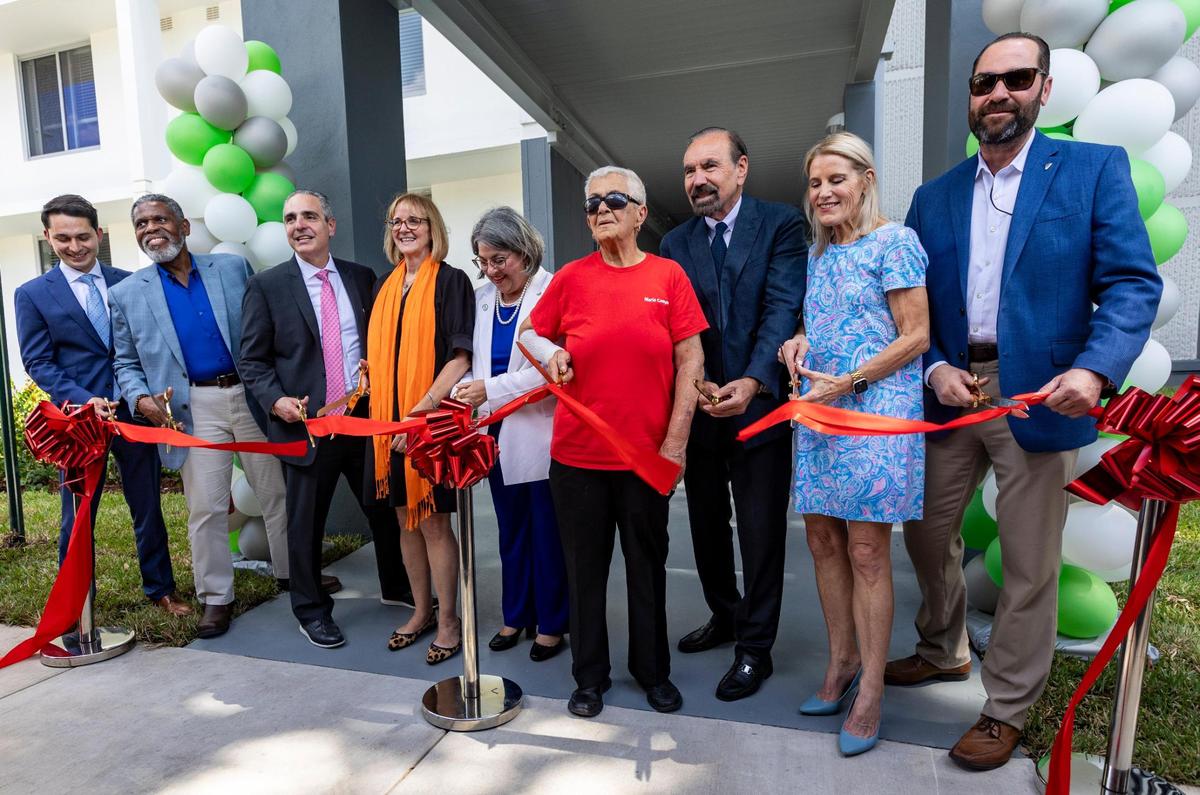 “Hemos trabajado incansablemente para encontrar soluciones”, dijo la alcaldesa Daniella Levine Cava (centro). Funcionarios electos e invitados especiales cortan la cinta frente a la entrada de Robert King High durante la inauguración del edificio recientemente renovado. “Hemos cogido viviendas asequibles que están en mal estado y las estamos convirtiendo en algo hermoso, además de agregar nuevas unidades”.