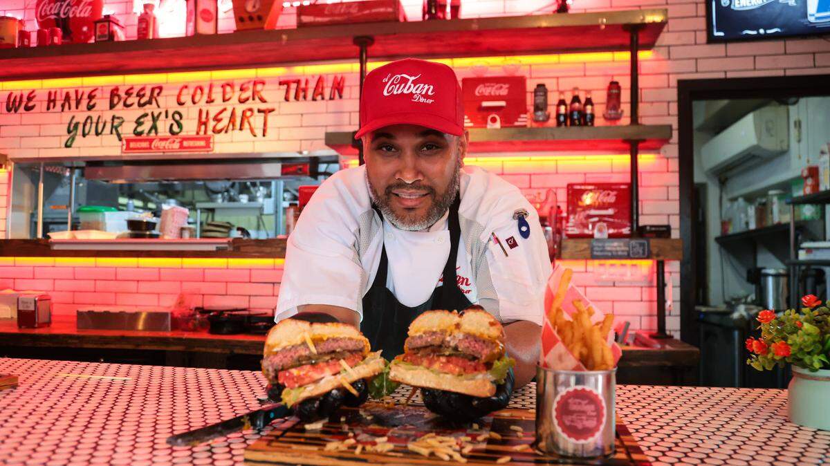 GastronomicaMiami Executive Chef Yasmani Lorenzo Ochoa holds the hamburger dish, a beef patty of American wagyu round, grilled with melted cheese and topped with pickles, tomatoes, lettuce and caramelized onions, at El Cuban Diner at 1620 SW Eighth St., in Miami, Fla., on Tuesday, Nov. 4, 2025.
