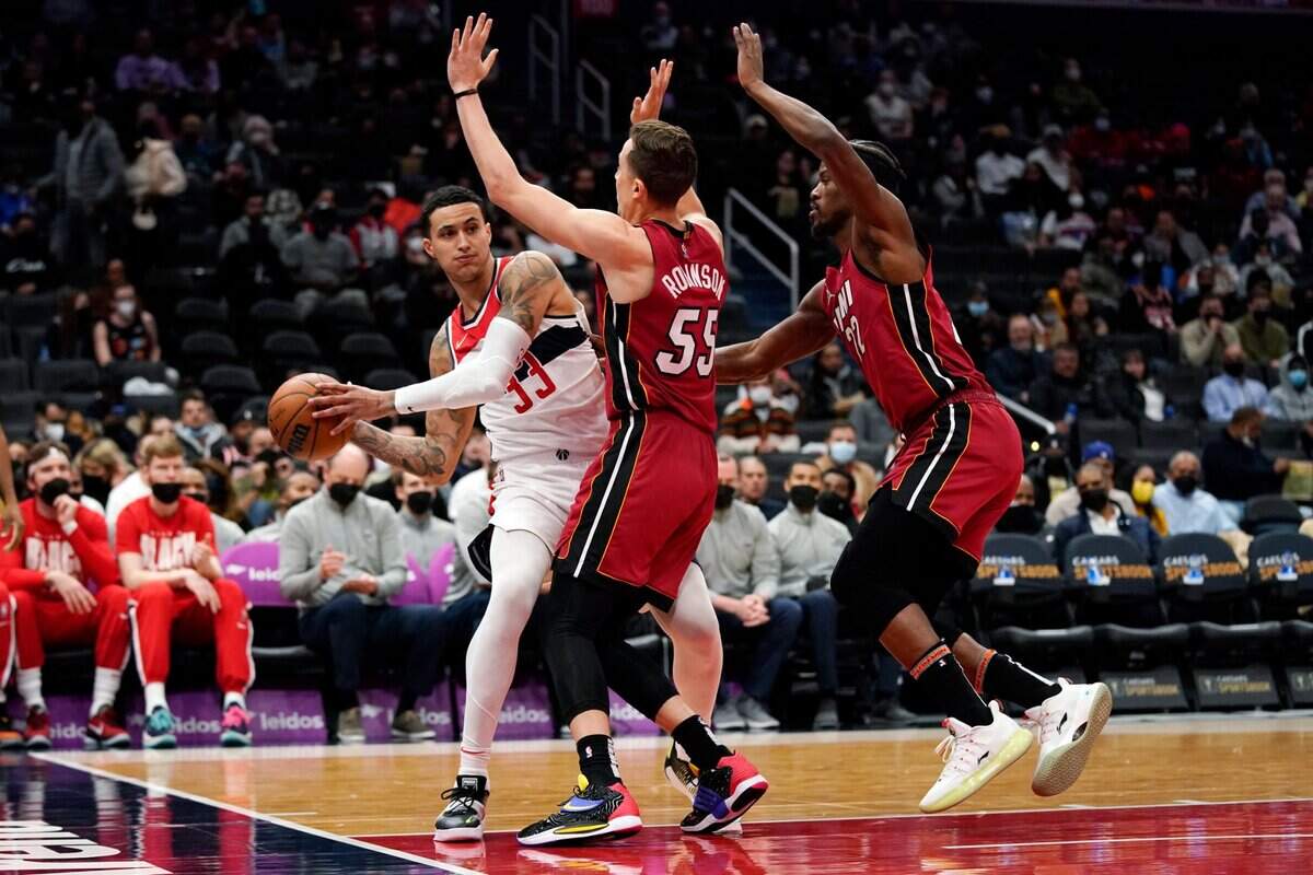 El jugador de los Wizards Kyle Kuzma (izq.) trata de pasar la pelota ante la marca de Duncan Robinson (centro) y Jimmy Butler, del Heat de Miami, en el partido celebrado el 7 de febrero de 2022 en Washington.