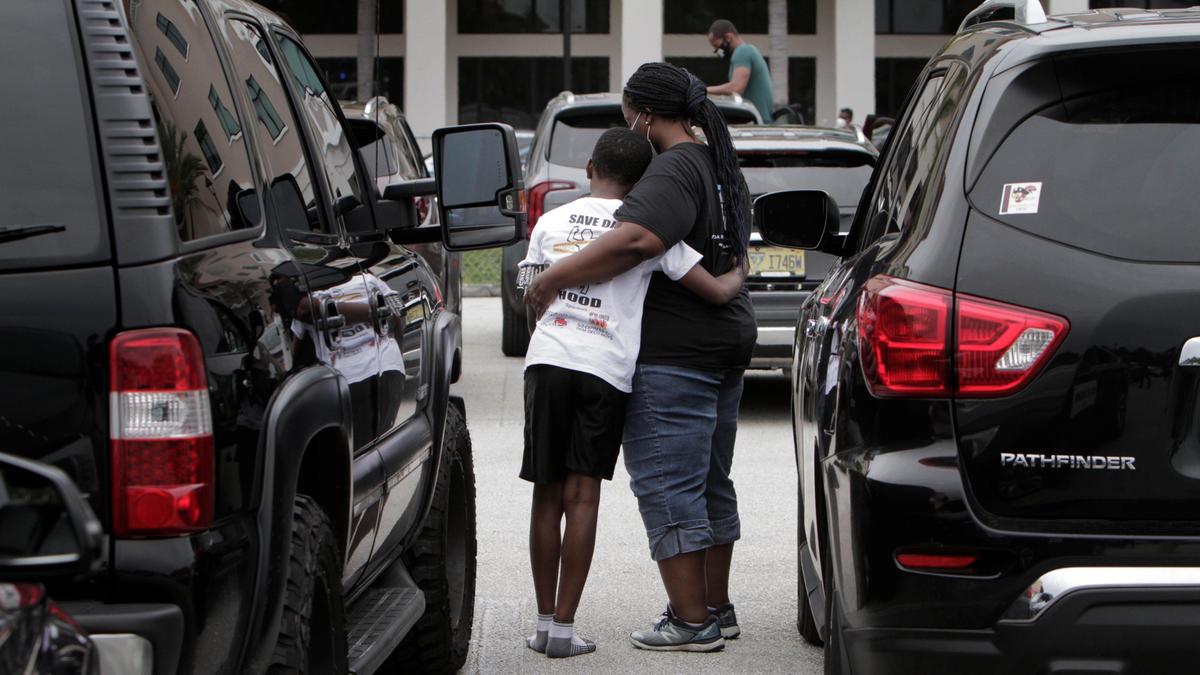 Rosemine Lederl, right, and her son Jahel Alexis pray together in the parking lot at Miramar Town Center.