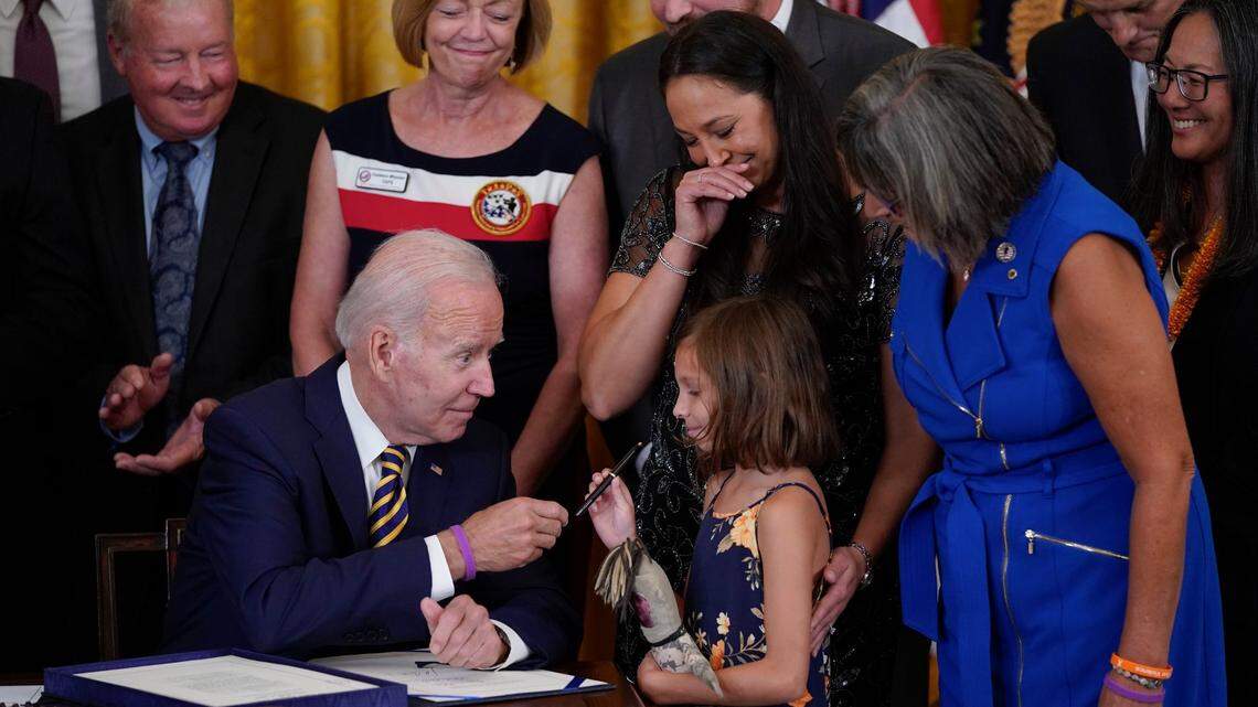 El presidente Joe Biden le da el bolígrafo que usó para firmar la “Ley PACT de 2022” a Brielle Robinson, hija del Sargento de Primera Clase Heath Robinson, quien murió de cáncer hace dos años, durante una ceremonia en el Salón Este de la Casa Blanca, el miércoles 10 de agosto de 2022, en Washington. (Foto AP/Evan Vucci)