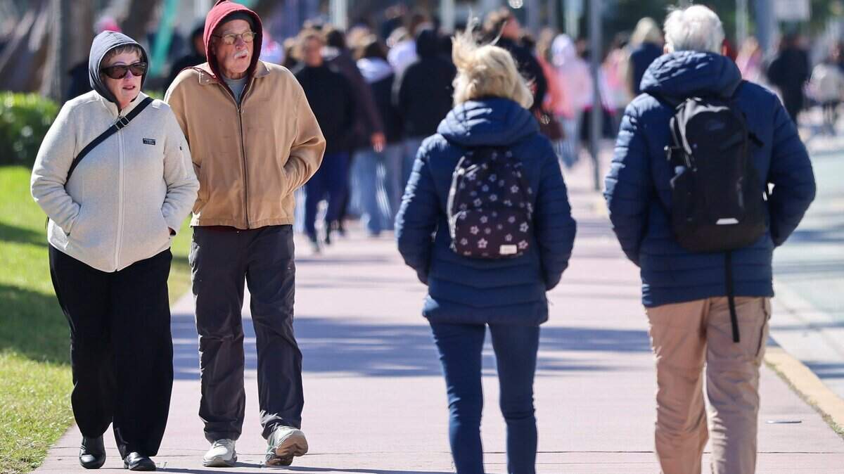 Los turistas caminan, comen y visitan la playa mientras una ola de frío desciende sobre el sur de Florida durante su visita al Distrito Art Decó de Miami Beach.