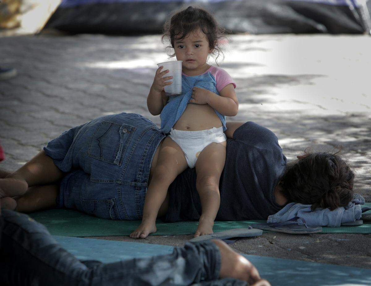 Una niña descansa junto a su madre en un pequeño campamento para migrantes justo a la entrada del Puente Internacional Gateway, en Matamoros, México.