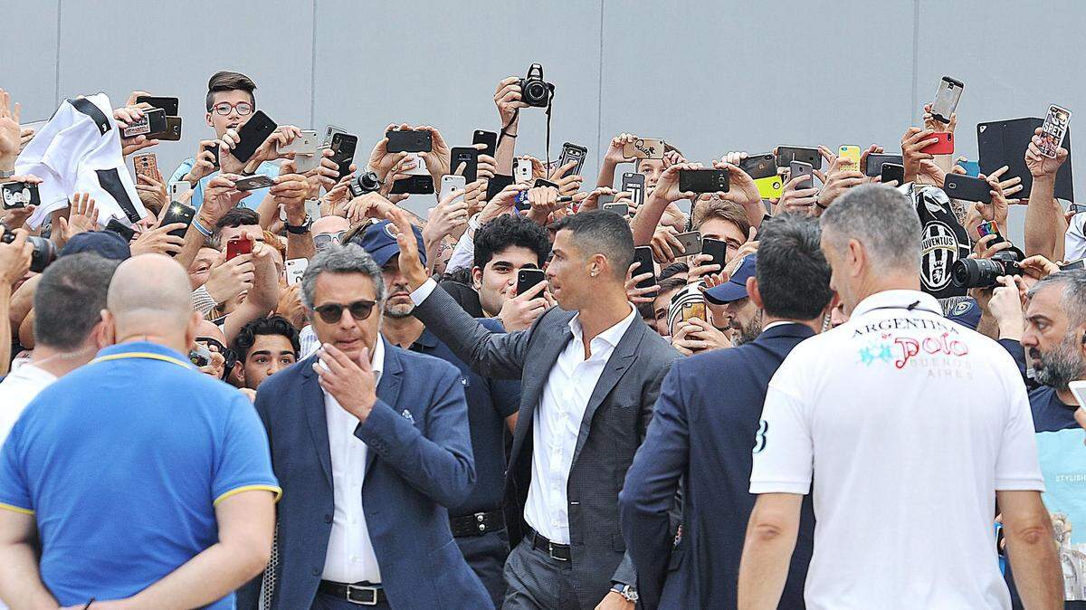 El portugués Cristiano Ronaldo (centro) saluda a los aficionados que le aguardaban a su llegada al J Medical, la clínica de propiedad del Juventus, para someterse al reconocimiento médico previo a la formalización de su fichaje por el conjunto de Turín, el  16 de junio de 2018.