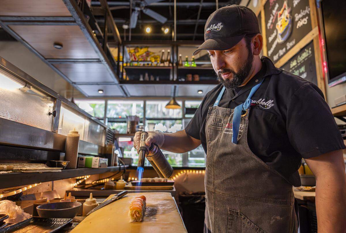 El chef Pedro Barahona prepara un rollo de sake aburi en Pubbelly Sushi. El rollo lleva kanikama, salmón sellado, yuzu miso, aceite de trufa y shichimi.