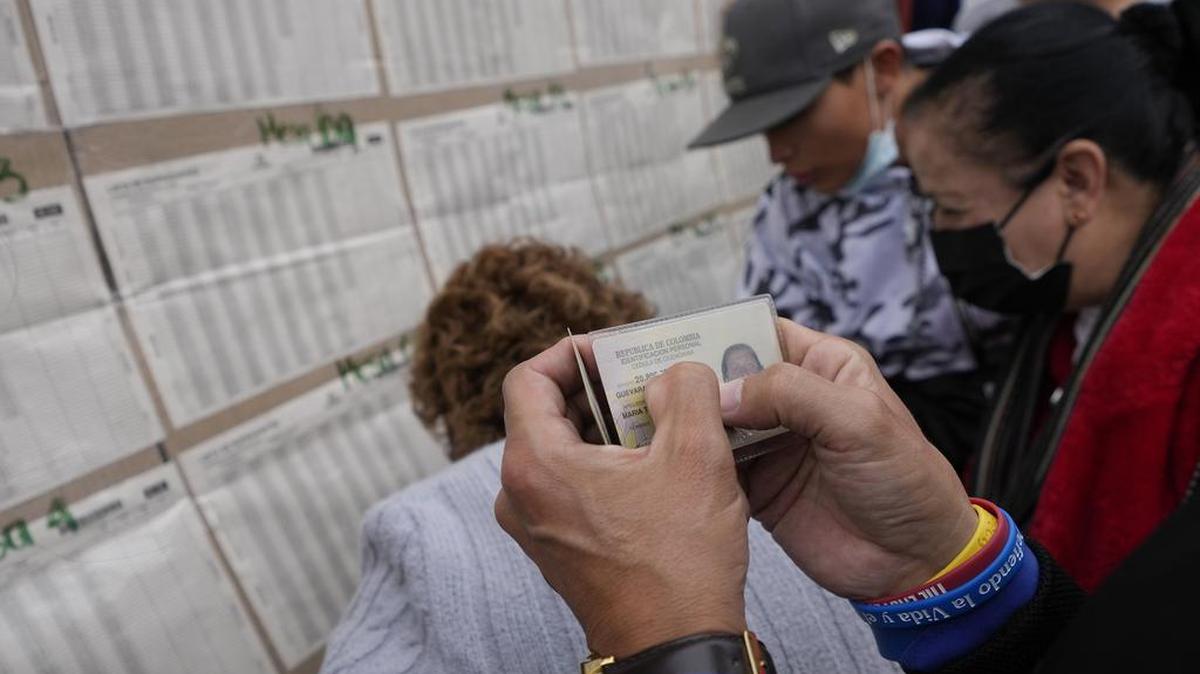 La gente revisa una lista de votantes para confirmar dónde deben depositar sus votos durante las elecciones legislativas en Bogotá, Colombia, el domingo 13 de marzo de 2022. (Foto AP/Fernando Vergara)