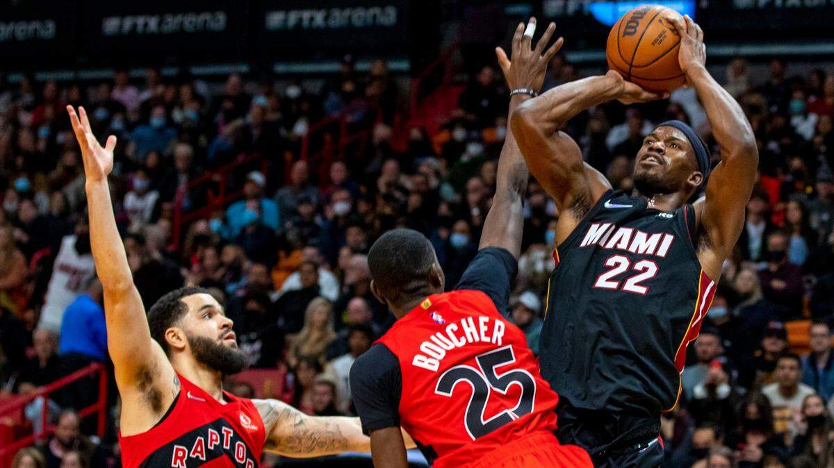 Miami Heat forward Jimmy Butler (22) shoots over Toronto Raptors forward Chris Boucher (25) and Fred VanVleet (23) during the second quarter of an NBA game at FTX Arena in Downtown Miami, Florida, on Saturday, January 29, 2022.