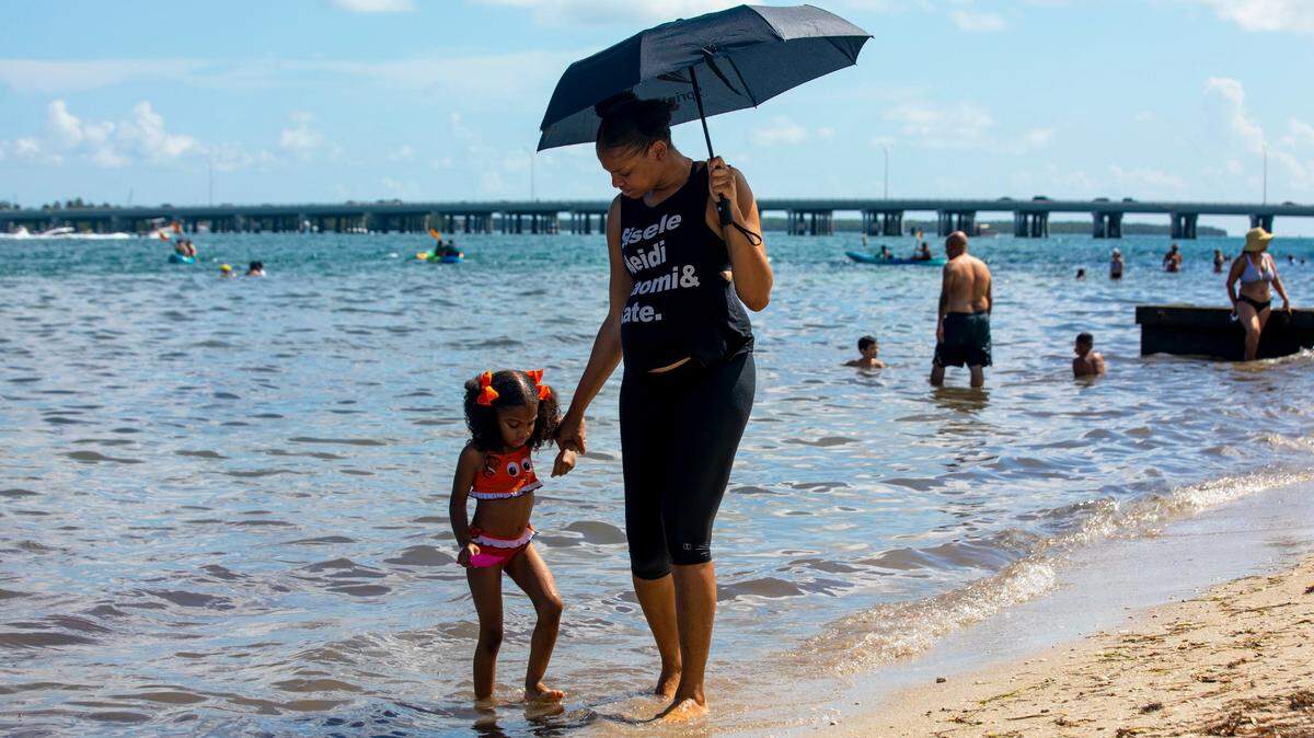 Chimene Purdy, de 36 años, camina con su hija Naomi Jackson, de 5 años, por la orilla de la playa en Virginia Key Beach Park, el sábado 8 de agosto de 2020.