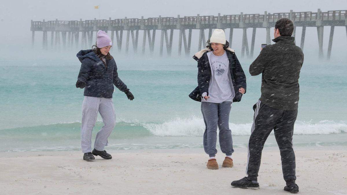 Los hermanos Page, Sadie, de 17 años, Olivia, de 19, y Jaxson, de 22, de Gulf Breeze, graban un video para TikTok junto a la orilla mientras cae nieve en Pensacola Beach el martes 21 de enero de 2025.