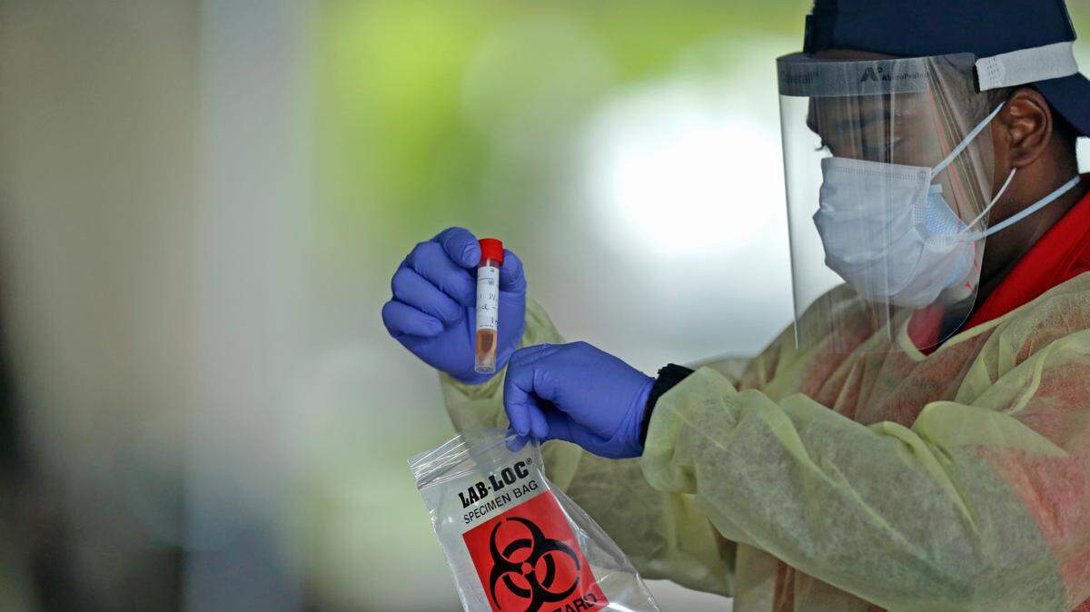 Un trabajador de salud de American Medical Response sostiene una prueba de COVID-19 de pacientes del centro de pruebas en Holiday Park ubicado en 1150 G. Harold Martin Drive en Fort Lauderdale el jueves 30 de abril 2020.