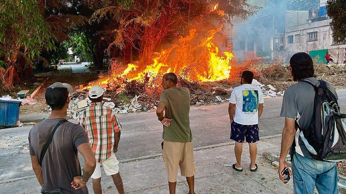 Residentes observan las llamas de un incendio en un vertedero de basura a cielo abierto en un barrio de La Habana, el 22 de febrero de 2026. El Ejército, llamado de emergencia a recoger montañas de basura de las calles.