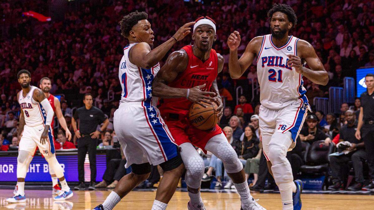 El astro del Heat Jimmy Butler (centro) trata de entrar al aro ante la marca de Kyle Lowry (izq.) y Joel Embiid, de los 76ers de Filadelfia, en el partido celebrado el 18 de noviembre de 2024 en Miami.