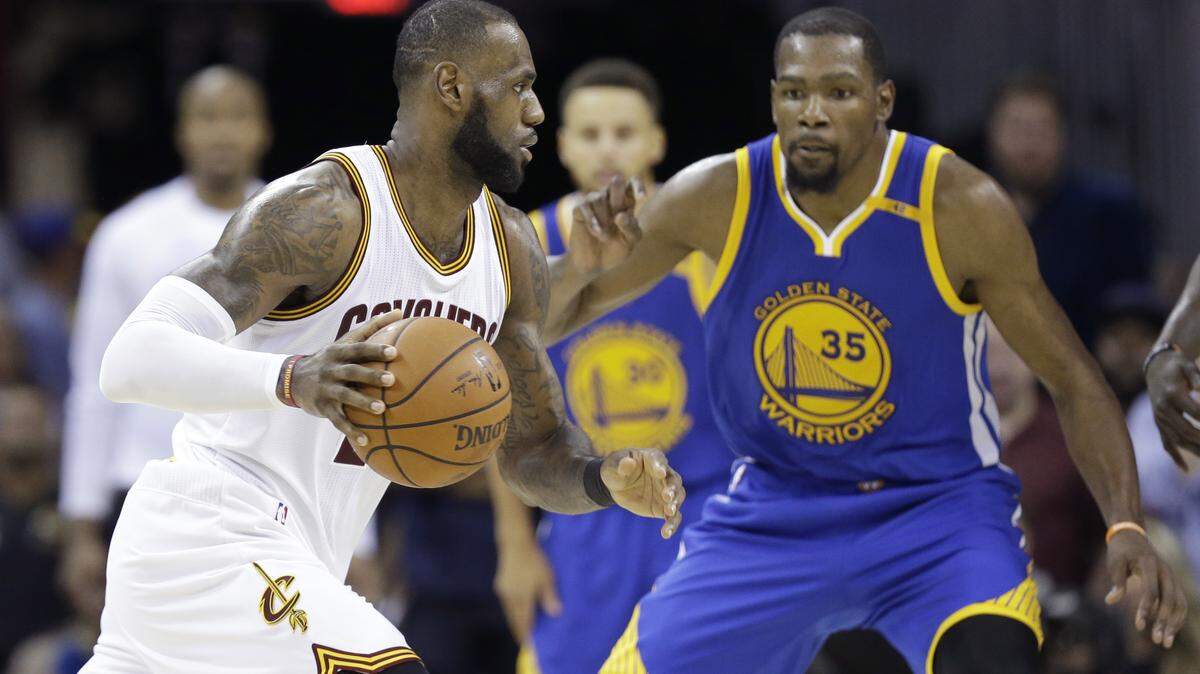 LeBron James, con los Cavaliers (izq.) tratar de escapar de la marca de Kevin Durant, de los Warriors, el 9 de junio del 2017 en Cleveland.