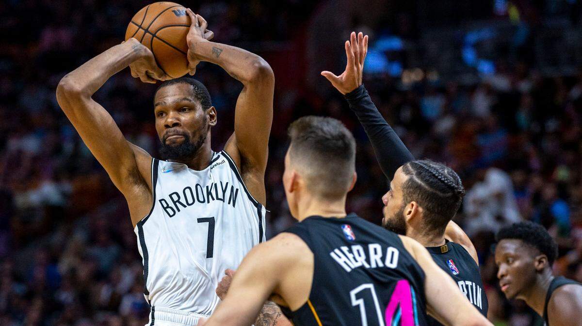 El jugador de los Nets de Brooklyn Kevin Durant (izq.) pasa la pelota ante la marca de Caleb Martin (centro) y Tyler Herro, del Heat, en el partido celebrado el 26 de marzo de 2022 en Miami.