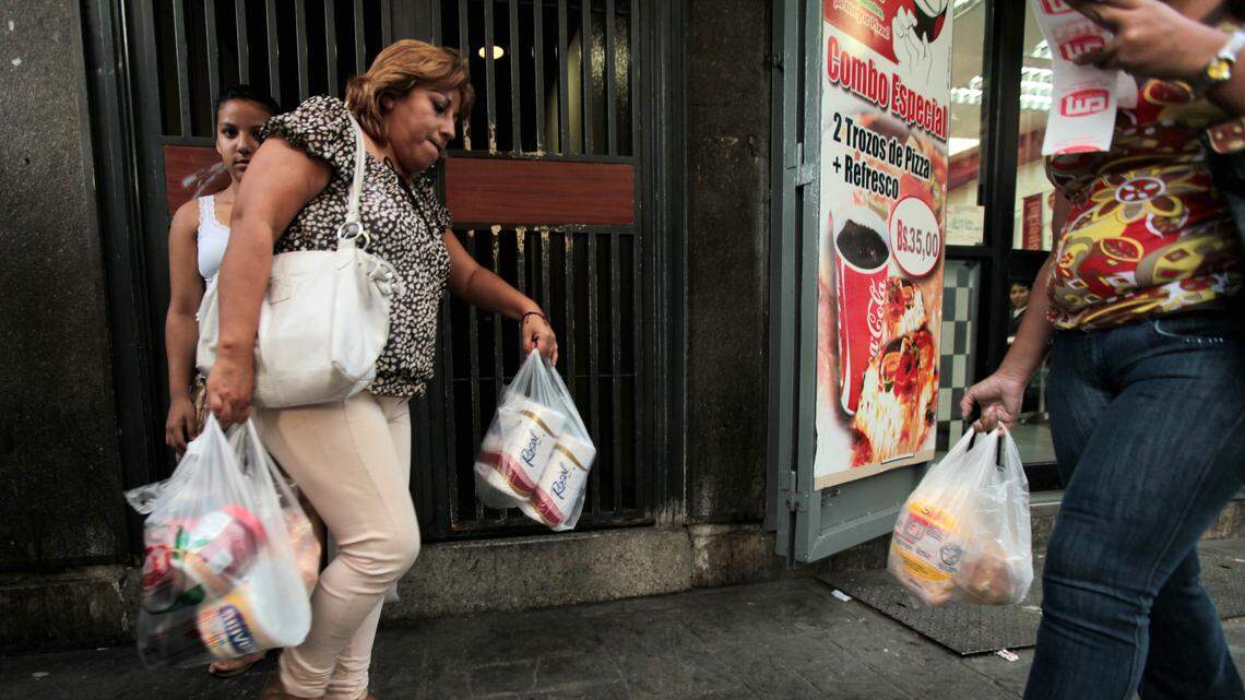 A woman leaves a market in Caracas, Venezuela.  About 40 percent of Venezuela’s stores have been forced to close, business owners say, after President Nicolás Maduro imposed a big hike in minimum wages.