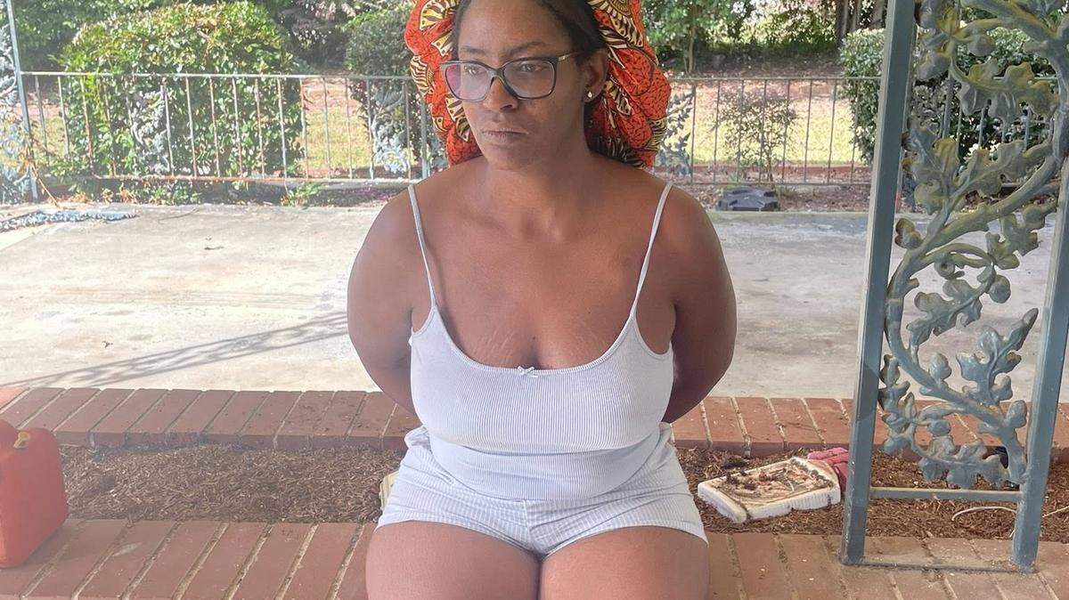 Timishea Price, miembro del concejo municipal de Reynolds, Georgia, se sienta, esposada, en un muro de ladrillos el miércoles.