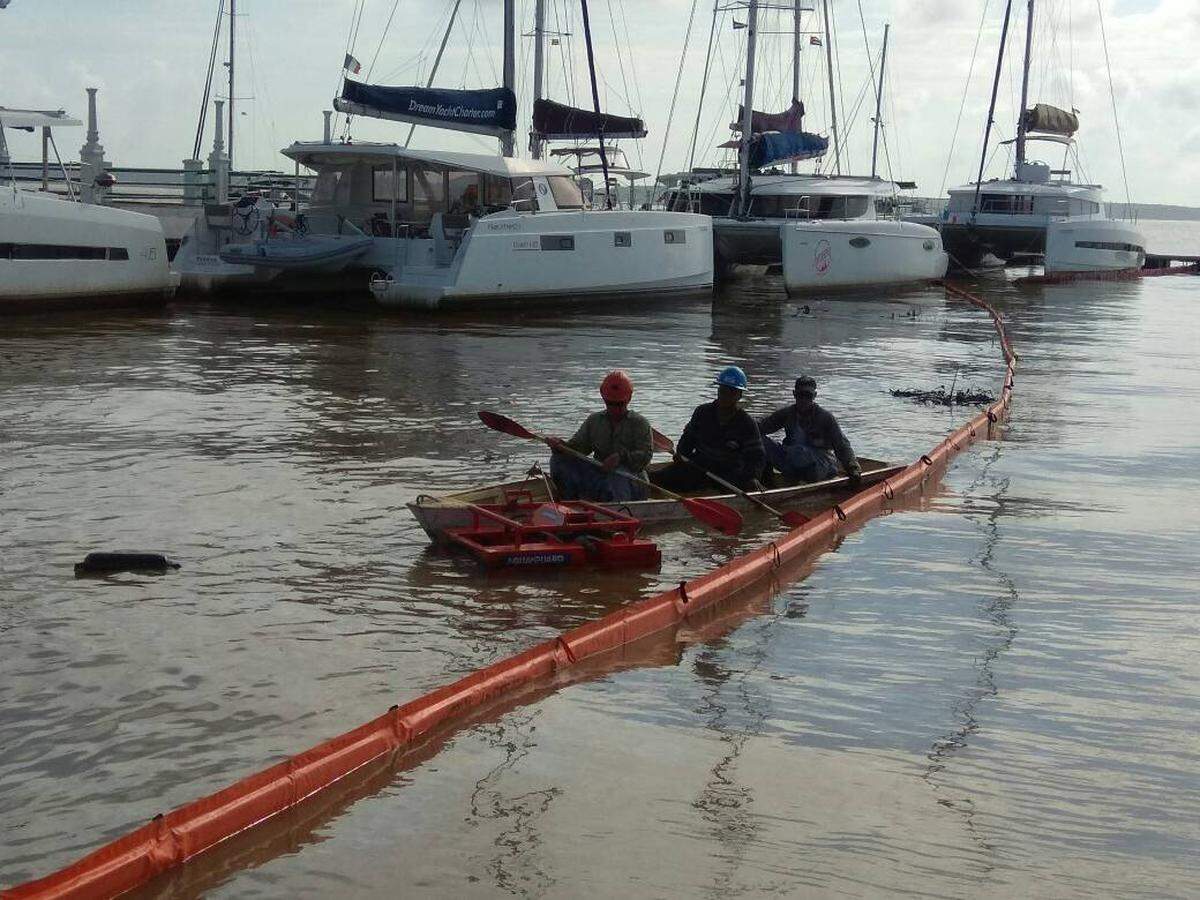 Trabajadores de Cuba Petróleo intentando revertir el daño medioambiental producido por el derrame de aguas oleosas en la bahía de Jagua.