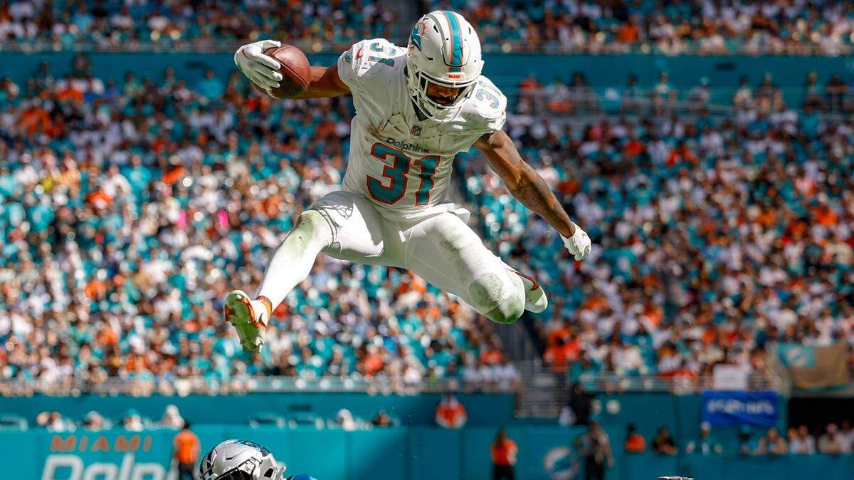El running back de los Dolphins Raheem Mostert salta para evitar la marca del cornerback de los Panthers de Carolina CJ Henderson, en el partido celebrado el 15 de octubre de 2023 en el Hard Rock Stadium en Miami Gardens, Florida.