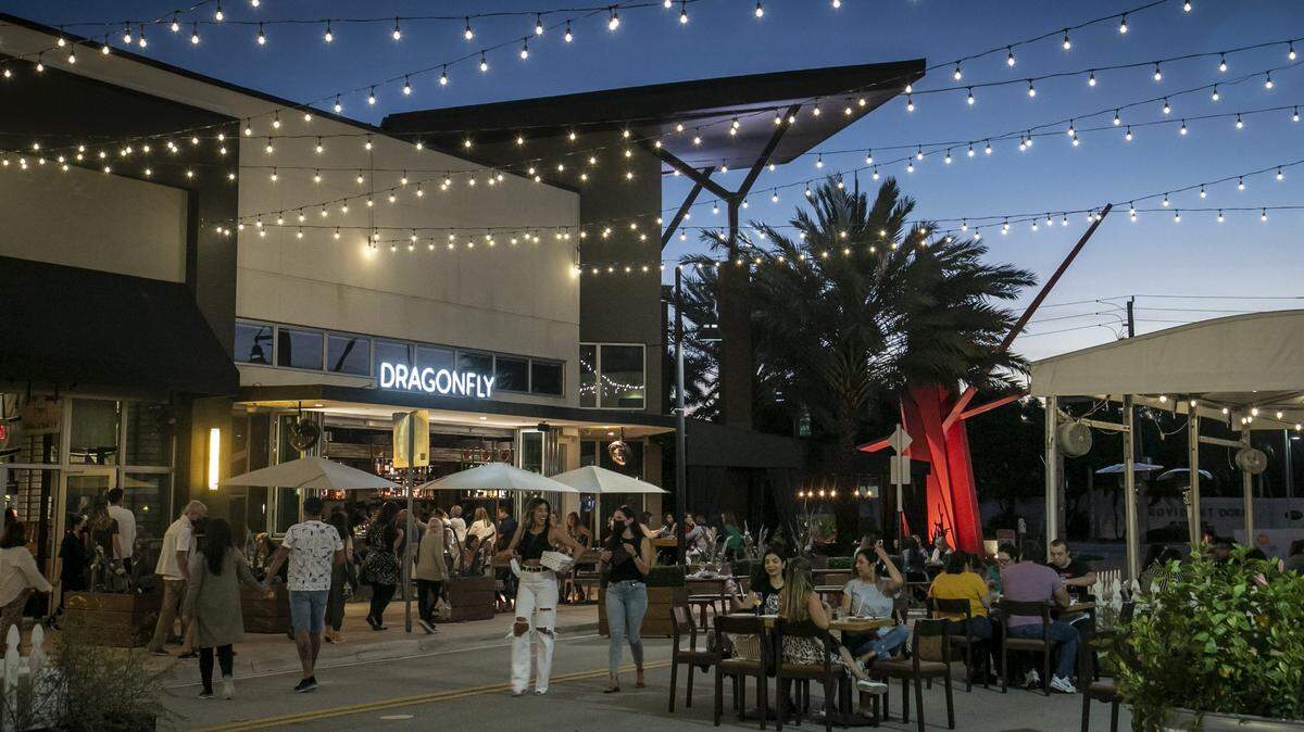 La gente disfruta de una cena al aire libre en la bulliciosa Main Street de Doral, en marzo de 2021. Doral ha evolucionado en los últimos años de un distrito de logística y almacenes a un lugar donde los residentes pueden vivir y trabajar. La ciudad está tratando de crear una reputación como nexo artístico, político y social.