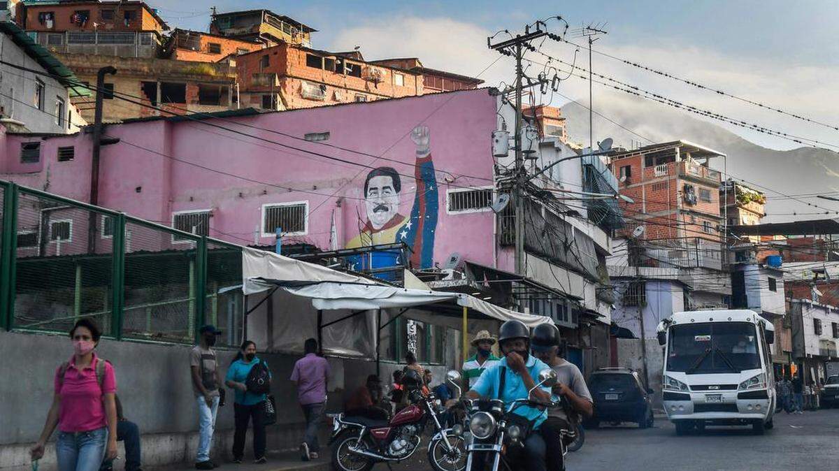 Los transeúntes pasan frente a un graffiti del presidente Nicolás Maduro, en el barrio de Petare en Caracas el 16 de septiembre de 2020.